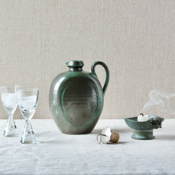 mood image of Swedish Art Deco ceramic bottle vase from Upsala Ekeby with copper glaze, with green Arne Bang candlestick and modernist Holmegaard glasses