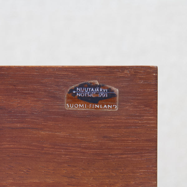 Zoomed in image showing Nuutajärvi Notsjo's manufacturer's stick. The makers mark features a fish and declares that the item was made in Suomi / Finland.