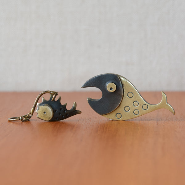 Pair of brass Walter Bosse fish designs including a bottle opener and keyring, each fish has patinated and polished areas